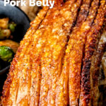 Close up crispy crackling on a slow roasted pork belly joint featuring a title overlay.