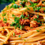 Close-up crumbled tofu pasta in a spiced tomato sauce featuring a title overlay.