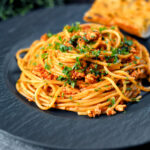 Crumbled tofu pasta in a spiced tomato sauce served with garlic bread.
