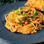 Crumbled tofu pasta in a spiced tomato sauce served with garlic bread.