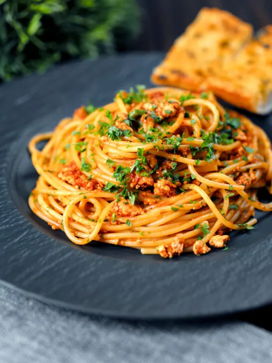Crumbled tofu pasta in a spiced tomato sauce served with garlic bread.