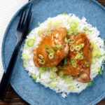 Overhead Filipino coconut milk chicken thigh adobo served with white rice featuring a title overlay.