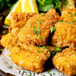 Close up fish goujons or nuggets made with monkfish served with lemon wedges.