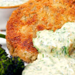 Close up fish cake served with homemade tartar sauce featuring a title overlay.