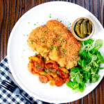 Kotlet schabowy or Polish pork schnitzel served with Hungarian lecsó and pickles.