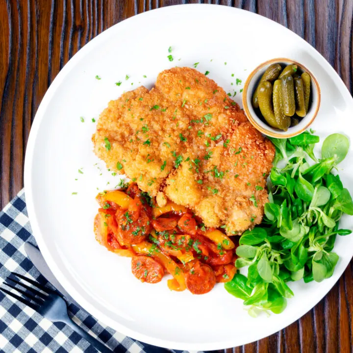 Kotlet schabowy or Polish pork schnitzel served with Hungarian lecsó and pickles.