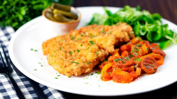 Kotlet schabowy or Polish pork schnitzel served with Hungarian lecsó and pickles.