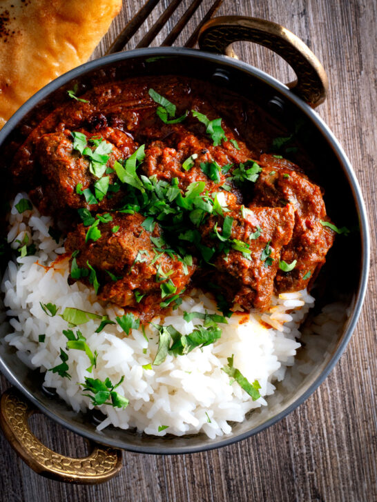 Overhead lamb rogan josh curry with rice, naan and fresh coriander.