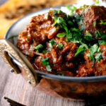 Lamb rogan josh curry with rice, naan and fresh coriander.