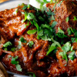 Close-up lamb rogan josh curry with rice and fresh coriander.