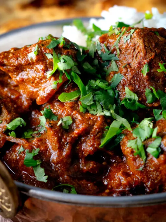 Close-up lamb rogan josh curry with rice and fresh coriander.