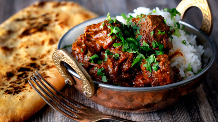 Kashmiri influenced lamb rogan josh curry served with rice and naan bread.