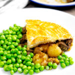 Traditional meat and potato pie served with garden peas.