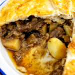 Close up of a meat and potato plate pie showing the filling.