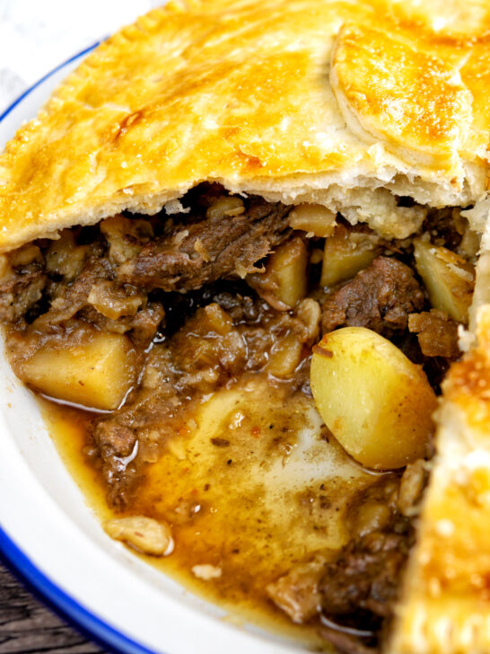 Close up of a meat and potato plate pie showing the filling.