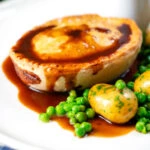 Homemade minced beef and onion pie served with peas and potatoes.