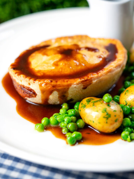 Homemade minced beef and onion pie served with peas and potatoes.