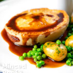 Homemade minced beef and onion pie served with peas and potatoes featuring a title overlay.
