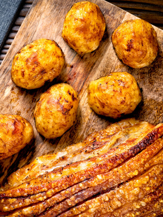 Overhead roast potatoes served along side roasted pork belly with crispy crackling.