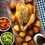 Overhead perfect Sunday roast chicken with roast potatoes, stuffing balls, veggies and gravy.