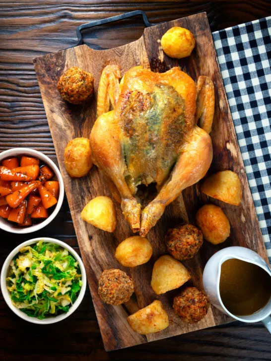 Overhead perfect Sunday roast chicken with roast potatoes, stuffing balls, veggies and gravy.