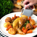 Pan gravy poured over a roasted chicken Sunday lunch with all of the trimmings.