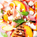 Close-up overhead main course summer salad with pickled peaches, ham and goats cheese.