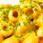 Close-up roasted butternut squash pasta garnished with snipped chives.