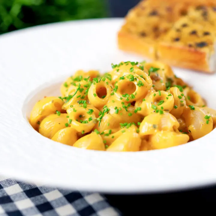 Creamy roasted butternut squash pasta with garlic bread garnished with snipped chives.