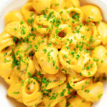 Overhead close-up roasted butternut squash pasta garnished with snipped chives.