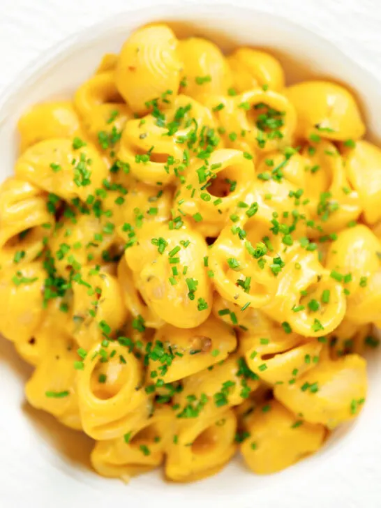 Overhead close-up roasted butternut squash pasta garnished with snipped chives.