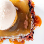 Overhead sticky toffee pudding served with caramel sauce and vanilla ice cream.