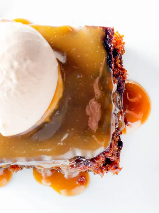 Overhead sticky toffee pudding served with caramel sauce and vanilla ice cream.