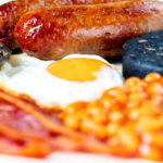 Close-up of sausages as part of full English fry up breakfast.