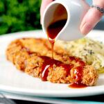 "Homemade" katsu sauce being poured over crispy Japanese Tonkatsu pork cutlet.
