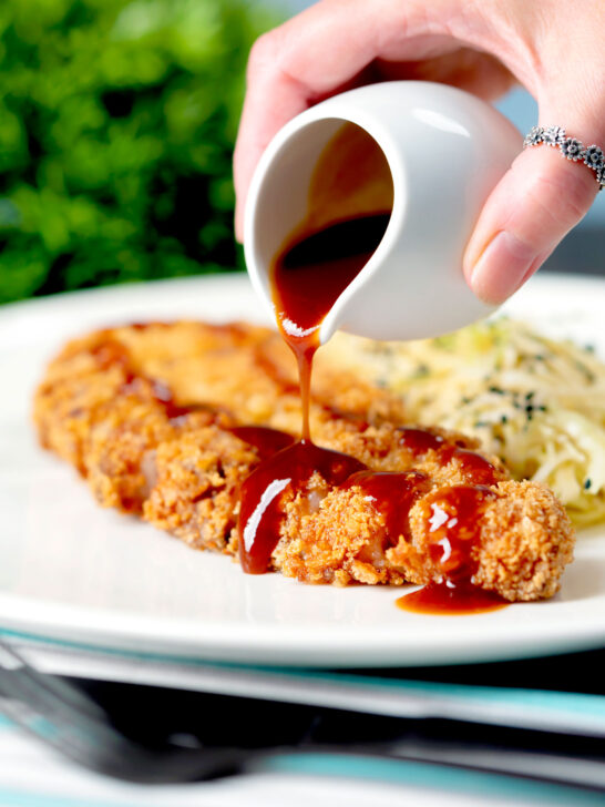 "Homemade" katsu sauce being poured over crispy Japanese Tonkatsu pork cutlet.