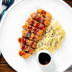 Overhead Japanese Tonkatsu pork cutlet served with katsu sauce and "soused" cabbage.