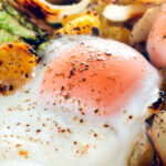 Close-up baked eggs in a a vegetarian left over cabbage and potato bake.