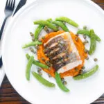 Overhead baked or roasted hake with romesco sauce, capers and sugar snap peas.