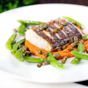 Baked hake fillet with romesco sauce and saut&eacute;ed sugar snap peas and capers.