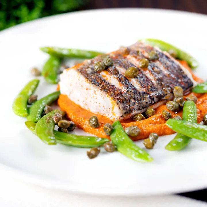 Baked hake fillet with romesco sauce and sautéed sugar snap peas and capers.
