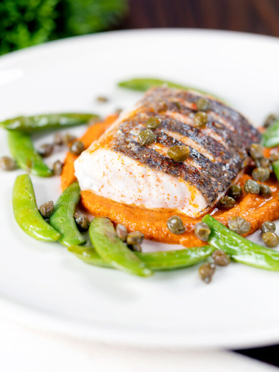 Baked or roasted hake with romesco sauce, capers and sugar snap peas.