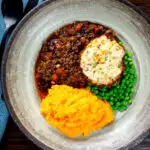 Overhead mince and dumplings stew served with swede and carrot mash featuring a title overlay.