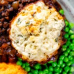 Close-up overhead suet dumpling on a minced beef stew, with peas and swede & carrot mash.