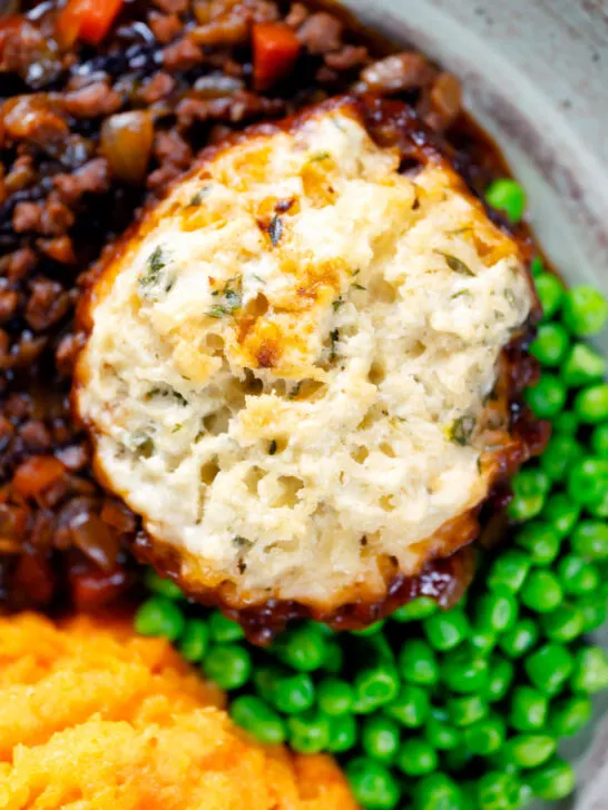 Close-up overhead suet dumpling on a minced beef stew, with peas and swede & carrot mash.