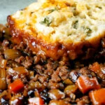 Close-up suet dumpling served on a minced beef and onion stew.