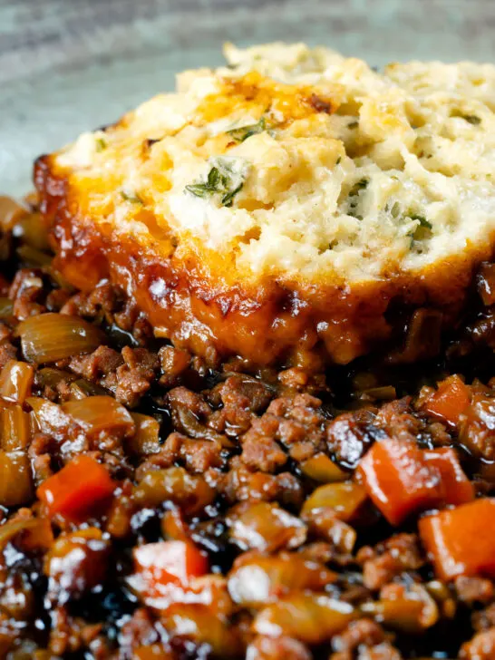 Close-up suet dumpling served on a minced beef and onion stew.