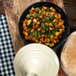 Overhead chickpea tagine with courgettes, harissa and preserved lemons served with flatbreads.