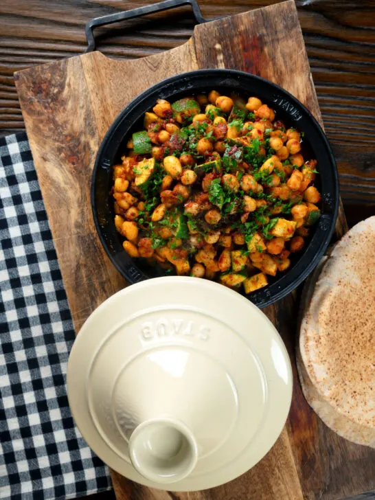 Overhead chickpea tagine with courgettes, harissa and preserved lemons served with flatbreads.