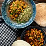 Overhead chickpea tagine with courgettes, harissa, and preserved lemons served with couscous.